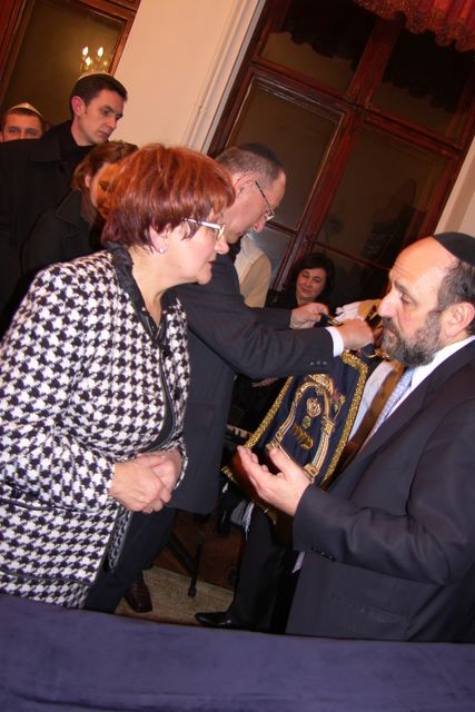 Alicja Kobus przekazuje Michaelowi Schudrichowi Mizrah do zawieszenia na wschodniej ścianie Domu Modlitwy