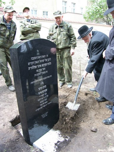 rabin Schlezinger kładzie pierwszą warstwę ziemi na grobie Akivy Egera